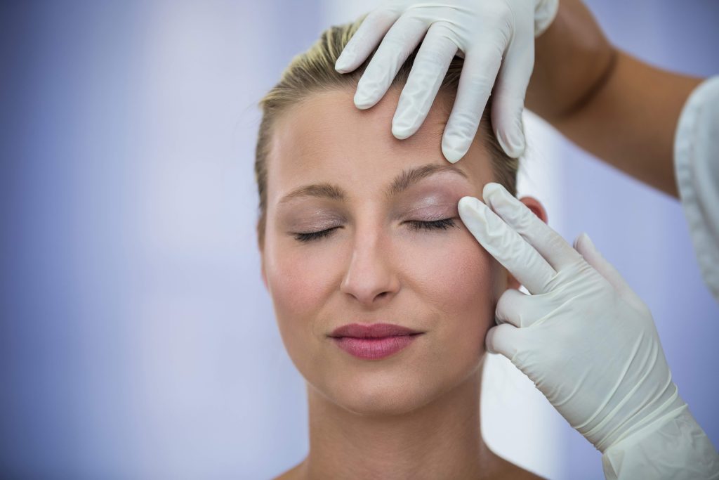 doctor examining female patients face from cosmetic treatment